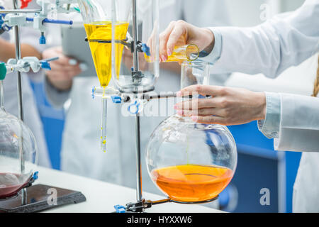 Close-up vista parziale della donna scienziato rendendo esperimento in laboratorio chimico Foto Stock