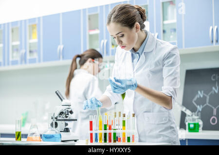 Femmina gli scienziati che lavorano con reagenti in tubi di test in laboratorio chimico Foto Stock