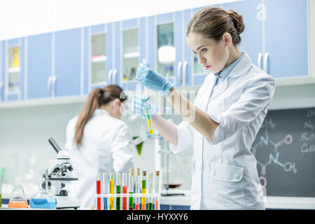 Donna scienziato tenendo il tubo di prova con il reagente di laboratorio chimico Foto Stock