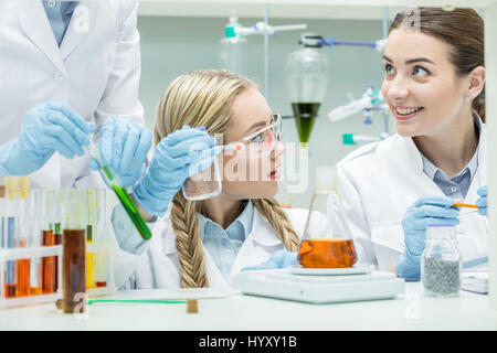 Giovani scienziati femmina facendo esperimento in laboratorio chimico Foto Stock
