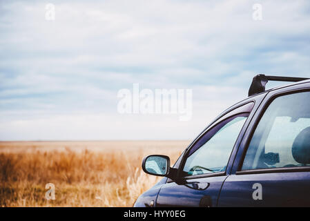 Macchina parcheggiata in prati e coperto con gocce di pioggia Foto Stock