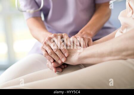 Lavoratore di cura tenendo alti donna con le mani in mano. Foto Stock