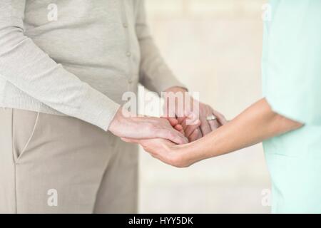 Lavoratore di cura tenendo alti donna con le mani in mano. Foto Stock