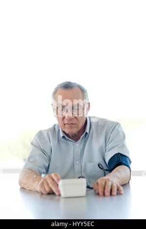Senior uomo prendendo la sua pressione del sangue. Foto Stock