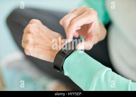 Donna senior con tracker di fitness sul polso. Foto Stock