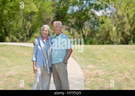 Coppia senior in piedi nel parco, sorridente. Foto Stock