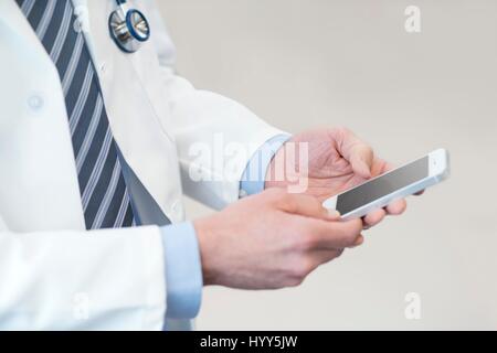 Medico maschio utilizza lo smartphone. Foto Stock