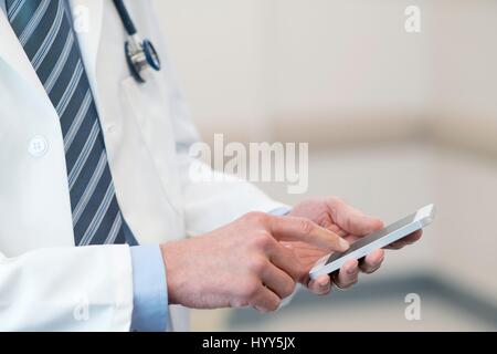Medico maschio utilizza lo smartphone. Foto Stock