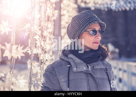 Donna che indossa un cappello e occhiali da sole in piedi all'aperto in inverno Foto Stock