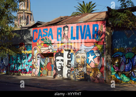 Colorati murali decorare una strada nel Barrio Brasil, Santiago del Cile. Il campanile della chiesa storica, Iglesia Corpus Dominco, in background. Foto Stock
