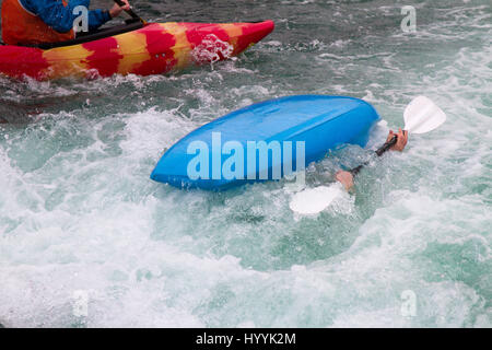 Oltre girato kayak barca in acqua grezza che mostra due mani in presa sulla pala Foto Stock