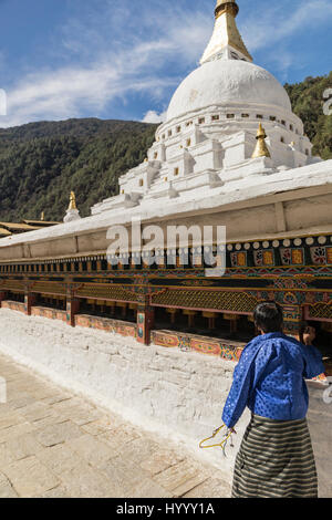 Donna bhutanesi girando le ruote di preghiera (Bhutan) Foto Stock