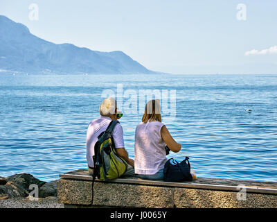 Giovane seduto sul banco alla diga del Lago di Ginevra a Montreux, canton Vaud, Svizzera Foto Stock