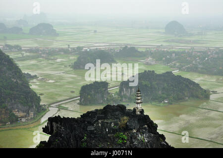 Panorama di campi di riso, rocce calcaree e cima pagoda da appendere Mua punto di vista Tempio in un giorno di pioggia. Ninh Binh, Vietnam Foto Stock