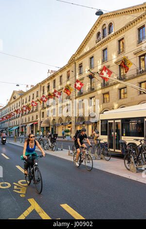 Ginevra, Svizzera - 30 agosto 2016: Tram e gente in bicicletta su Rue de la Corraterie Street con le bandiere della Svizzera nel centro della città di Ginevra, S Foto Stock