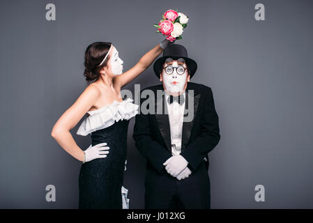 Attore comico e attrice in posa con bouquet di fiori. Mime esecutori di teatro di posa. La pantomima artisti Foto Stock