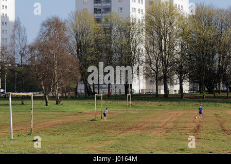 Blairdardie Park Keal Avenue, due ragazzi durante le vacanze di Pasqua Specchiatura di Pasqua giocando a calcio all'ombra dei progetti Foto Stock