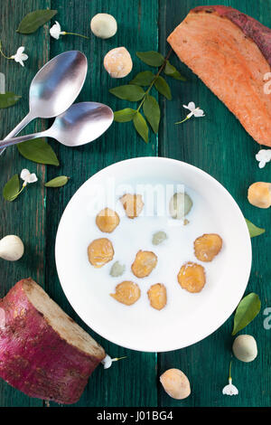 Giapponese di patate dolci gnocco di latte di cocco Thai dessert con piatto laici sullo sfondo di legno Foto Stock