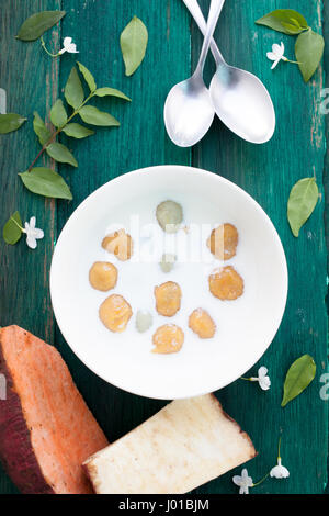 Giapponese di patate dolci gnocco di latte di cocco Thai dessert con piatto laici sullo sfondo di legno Foto Stock