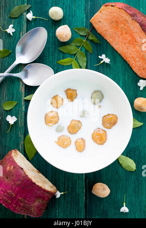 Giapponese di patate dolci gnocco di latte di cocco Thai dessert con piatto laici sullo sfondo di legno Foto Stock