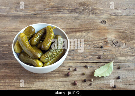 Pickles. Ciotola di cetriolini sottaceto (cetrioli) oltre rustico sfondo di legno vicino. Foto Stock