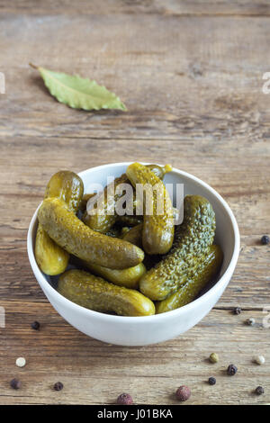 Pickles. Ciotola di cetriolini sottaceto (cetrioli) oltre rustico sfondo di legno vicino. Foto Stock