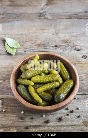 Pickles. Ciotola di cetriolini sottaceto (cetrioli) oltre rustico sfondo di legno vicino. Foto Stock