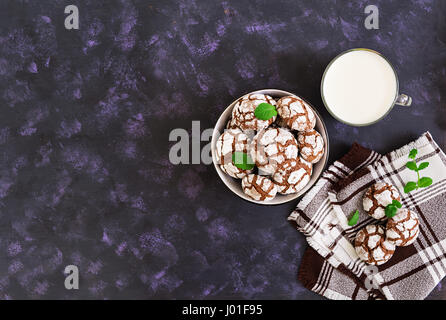 Biscotti al cioccolato e un bicchiere di latte su sfondo scuro. Vista superiore Foto Stock