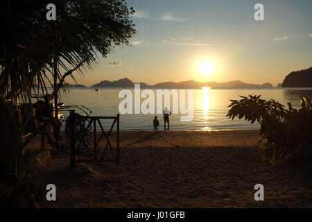 Due persone in spiaggia al tramonto in Palawan in un resort di cabine Foto Stock