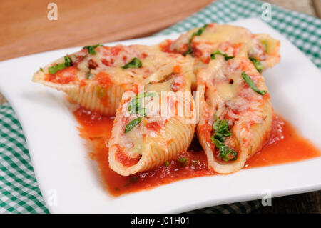 Pasta conchiglioni gusci di carne ripieni di carne macinata con spinaci e salsa di pomodoro , Formaggio Parmigiano, su di una piastra. Vista frontale. Foto Stock