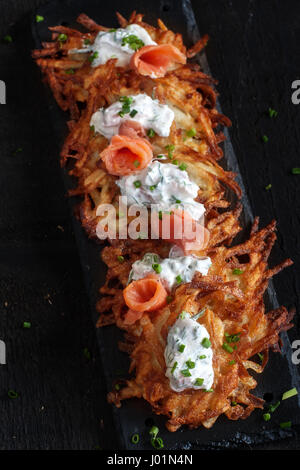 Tradizionale ebraica frittelle di patate latke rabboccato con salmone affumicato e crema di formaggio, aneto e erba cipollina. Foto Stock