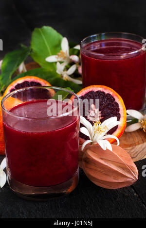 Spremuta fresca d'arancia rossa decorata con fiori d'arancio. Bassa foto chiave. Foto Stock