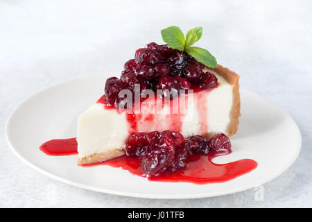 Cheesecake con ciliege acide e salsa di foglia di menta sulla piastra bianca Foto Stock