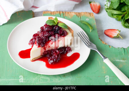 Cheesecake con salsa alle ciliegie sulla piastra bianca, primo piano Foto Stock