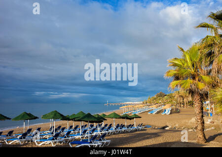 Spiaggia di Marbella, resort città sulla Costa del Sol in Andalusia, Spagna, lettini con ombrelloni da mare mediterraneo al mattino Foto Stock