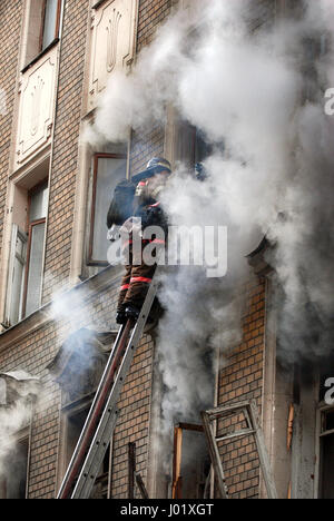 Vigile del fuoco si spegne un incendio in un edificio di appartamenti Foto Stock