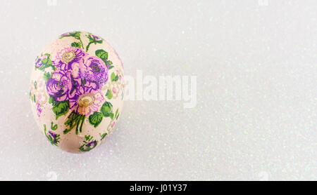 Decoupage colorato decorato uovo di pasqua contro argento lucido sfondo Foto Stock