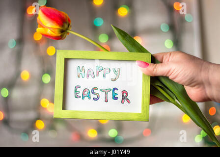 Mano azienda Felice Pasqua card e un rosso tulip Foto Stock