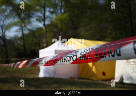 Rosso e bianco di linea di polizia intorno a una scena del crimine tenda in una foresta Foto Stock