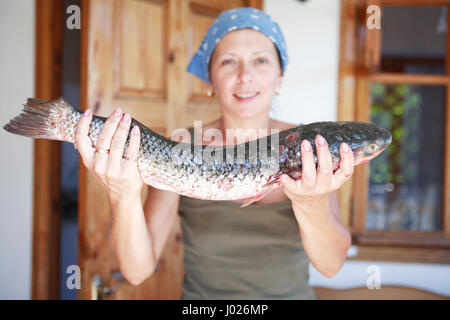 Bella donna matura con grandi fresco pesce crudo nella sua mano Foto Stock