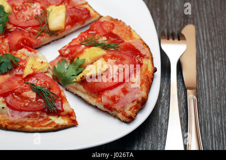 Primo piano della freschezza fette di pizza sulla piastra bianca vicino a forchetta e coltello Foto Stock