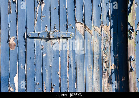 Squallido insiemi di garage o la fabbrica di porte in legno con peeling e sbiadita della vernice blu con il bianco e il rosso mattone colonne su un edificio vuoto in Avonmouth Foto Stock