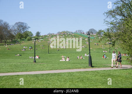 Persone in rilassante unseasonably caldo su Primrose Hill in primavera, London, England, Regno Unito Foto Stock