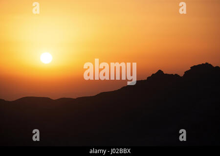 La natura e la vita all'aperto: un tramonto sul contorno scuro di una montagna Foto Stock