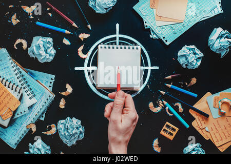 Ancora concettuale la vita con lo scrittore sul posto di lavoro, sharp matita rossa, notebook e annegare il simbolo di destinazione Foto Stock