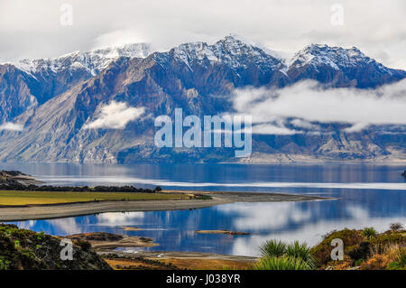 Nuvole basse giacente su un lago vicino a Wanaka nel sud della regione dei laghi di Nuova Zelanda Foto Stock