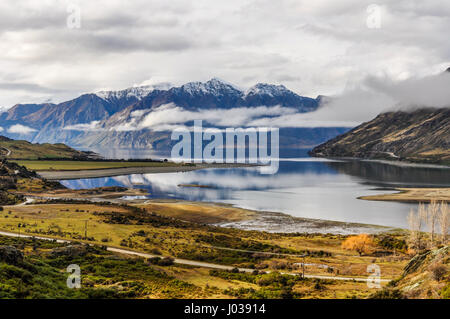 Nuvole basse giacente su un lago vicino a Wanaka nel sud della regione dei laghi di Nuova Zelanda Foto Stock