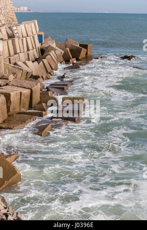 Le onde battono le rocce sul lungomare di La Caleta Beach a Cadiz, Spagna Foto Stock