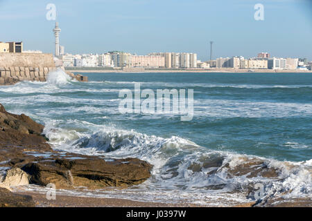 Le onde battono le rocce sul lungomare di La Caleta Beach a Cadiz, Spagna Foto Stock