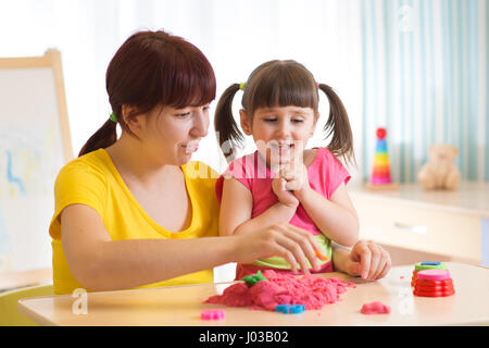 Carina ragazza del bambino e la madre gioca con la sabbia cinetica a casa Foto Stock